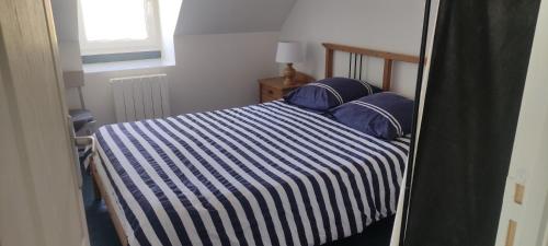 - une chambre dotée d'un lit avec une couverture rayée bleue et blanche dans l'établissement Maison Pleubian mer à pied, à Pleubian