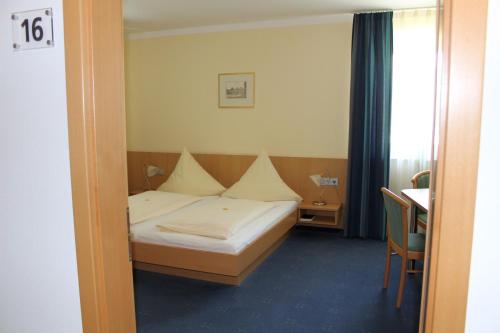 a bedroom with a bed and a table and a desk at Hotel Heike garni in Günzburg