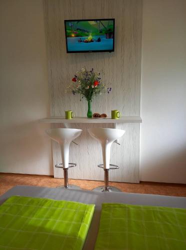 a room with a table with two stools and a tv at Afrodita in Štúrovo