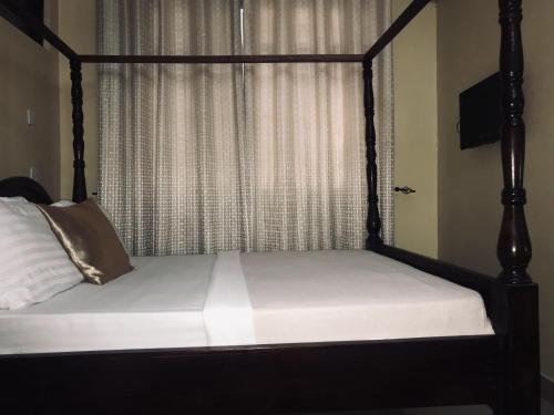 a bedroom with a bed with a four poster bed with a window at Transit Airport B&B in Dar es Salaam