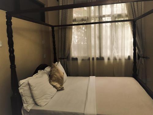 una camera con letto a baldacchino e finestra di Transit Airport B&B a Dar es Salaam