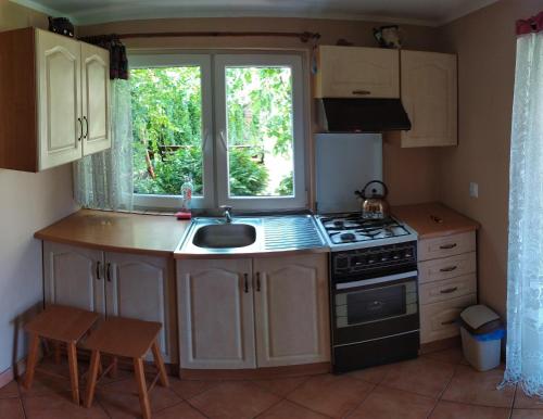 a kitchen with a sink and a stove and a window at Agroturystyka Jacnia in Jacnia