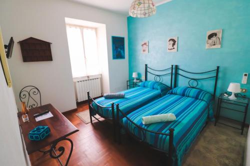 a blue bedroom with two beds and a table at Da Stea guest house in Coreglia Ligure