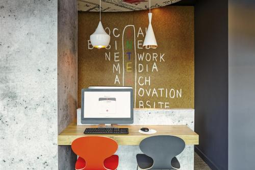 an office with a desk with a computer and two chairs at ibis Birmingham Airport Terminal Building - NEC in Bickenhill