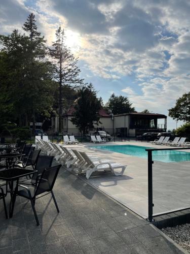 a swimming pool with lounge chairs and a table and chairsktop at Ośrodek Promenada- Faleza in Jastrzębia Góra