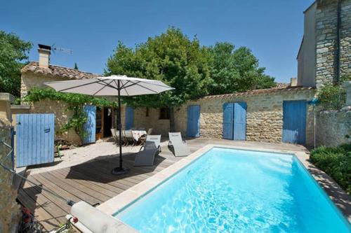 - une piscine avec un parasol, deux chaises, une table et un parasol dans l'établissement Maison de plain pied pour 4 pers piscine Lussan, à Lussan