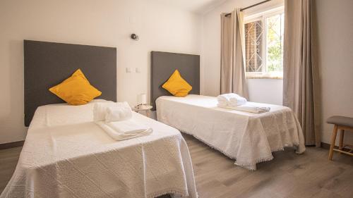 1 Schlafzimmer mit 2 Betten, gelben Kissen und einem Fenster in der Unterkunft Villa Pedro - Swimming Pool - BY BEDZY in Albufeira