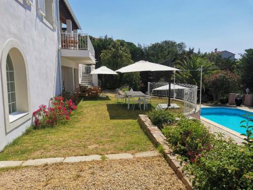 a garden with a table and umbrellas and a pool at Villa Via serena in Ajaccio