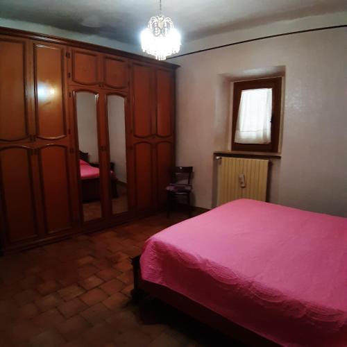 - une chambre avec un lit rose et des placards en bois dans l'établissement Residenza la Viola, à Casaprota