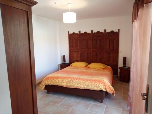1 dormitorio con 1 cama con cabecero de madera grande en Gîte L'Orangeraie - 2 Adultes - 2 enfants, en Elne