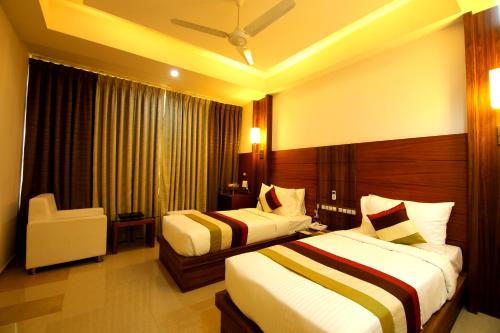 a hotel room with two beds and a chair at Hotel Hillway Park in Kollam