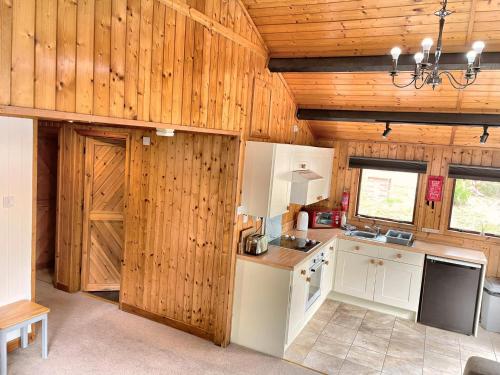 cocina con armarios blancos y paredes de madera en The Stag & Squirrel Lodge en Carmarthen