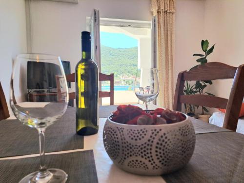 een tafel met een fles wijn en een fruitschaal bij Open Sea Apartmani in Grebaštica