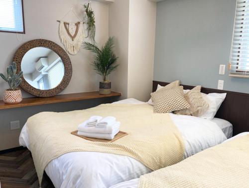 two beds in a bedroom with a mirror on the wall at TOMMY CONDOMINIUM WAKASA 401 in Naha