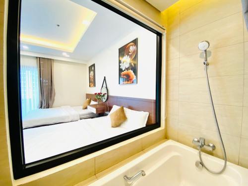 a bathroom with a large window over a bath tub at FLC SEA TOWER - Quy Nhơn in Quy Nhon