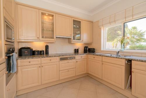 a kitchen with white cabinets and a window at Beautiful Villa on Boavista Golf Resort - Daily Service & Spa Access in Lagos