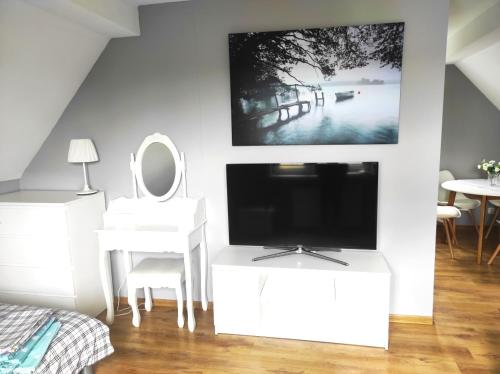 a white living room with a tv and a mirror at Noclegi w malowniczym Stryszowie in Stryszów