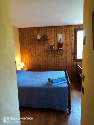 une chambre avec un lit bleu avec un mur en bois dans l'établissement Chambre La Lavandula Col de Turini, à Granges de Faisset