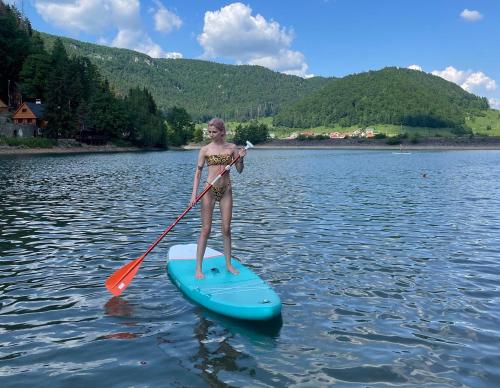a young girl on a paddle board on a lake at Hotel Priehrada in Dedinky