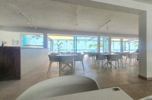 a dining room with tables and chairs and windows at Apartamento junto a la playa by Hugo Beach in Gandía