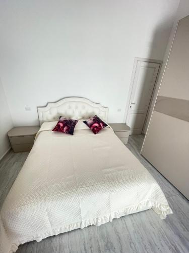 a white bed with two red pillows on it at La perla del mare in La Caletta