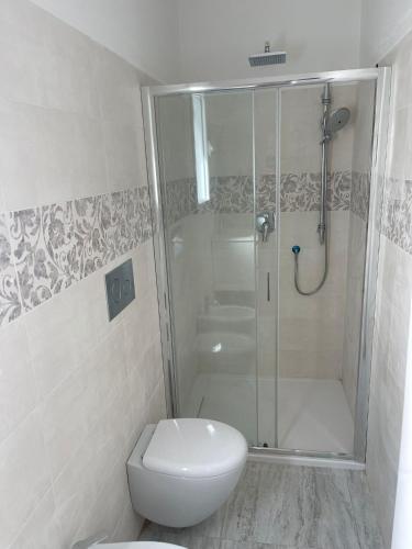 a white bathroom with a shower and a toilet at La perla del mare in La Caletta