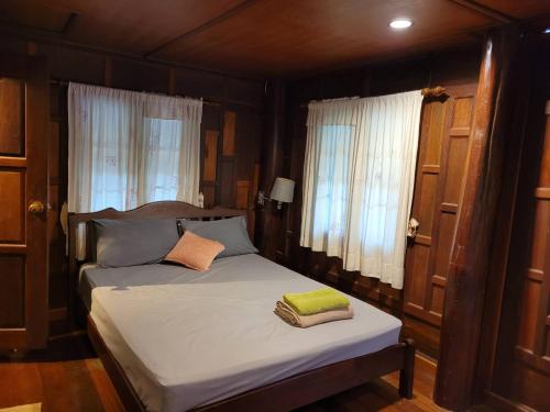 a bedroom with a bed with two towels on it at Ruenthai Ampawa in Samut Songkhram