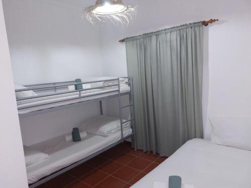 um quarto com 2 camas e um lustre em Gota D'agua Guest House em Vila Nova de Milfontes