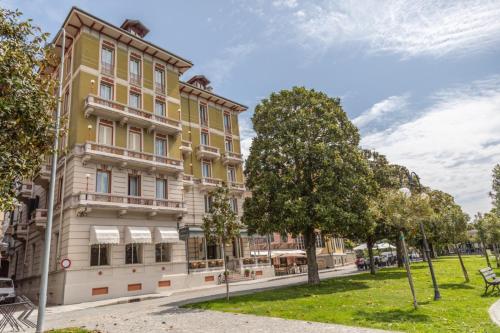 un grand bâtiment jaune avec des arbres devant lui dans l'établissement Hotel Pallanza, à Verbania