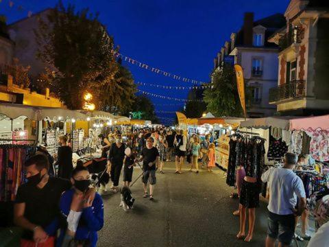 uma multidão de pessoas caminhando através de um mercado à noite em Champeix, maison confort 6 personnes em Champeix