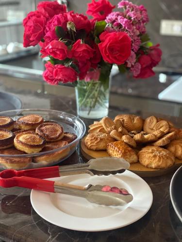 a table with a plate of pastries and a vase of flowers at Har-Mar Hotel in Goris