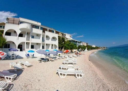a beach with chairs and umbrellas and a hotel at Luxurious Four Bedroom Beach Penthouse in Podstrana