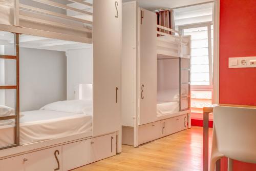 a bedroom with white bunk beds and a red wall at Generator Barcelona in Barcelona