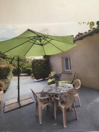 a table and chairs with a green umbrella on a patio at Gîte Moncherie in Colayrac-Saint-Cirq
