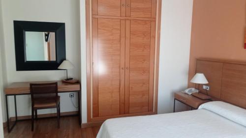 a bedroom with a bed and a desk with a mirror at Hotel Molino in Ronda