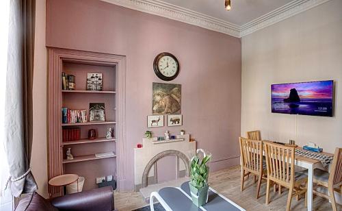 a living room with a table and a clock on the wall at Stylish Luxury 2-Bed Serviced Apartment in Heart of West End SSE Hydro Botanic Gardens in Glasgow
