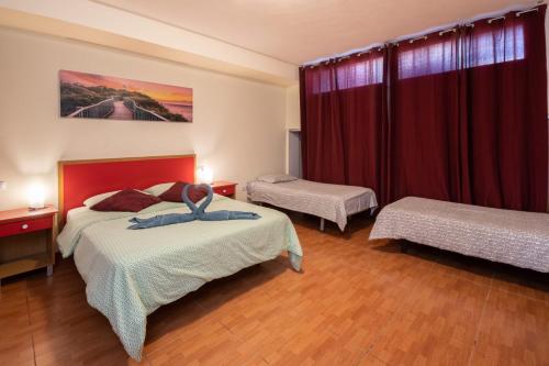 コティージョにあるEl Chulo Apartamentoのベッドが2つと赤いカーテンのある寝室