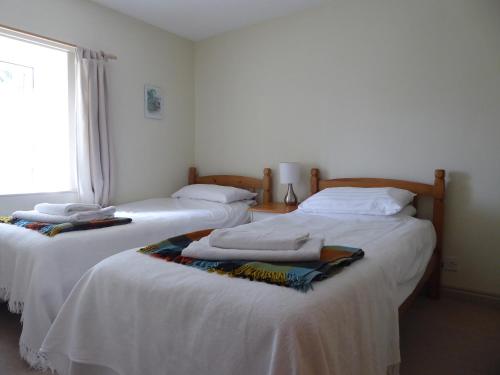 2 camas individuales en una habitación con ventana en Mews Cottage, en Middleton in Teesdale