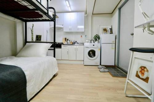 Seoul Central Namsan Studio 2Beds #102 في سول: غرفة نوم بسرير ومطبخ مع غسالة ملابس