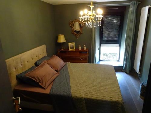 1 dormitorio con 1 cama con lámpara de araña y ventana en BOIS DE CHENES HOUSE en Phalsbourg