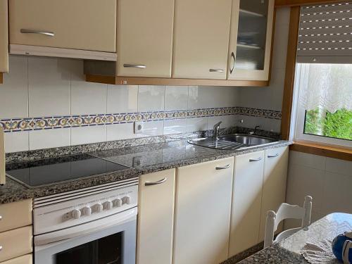 eine Küche mit weißen Schränken und einer Spüle in der Unterkunft Chalet Portosin con piscina al lado de la playa in Goyanes