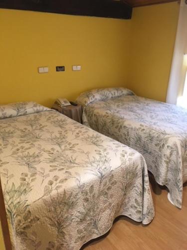 2 camas en una habitación con paredes amarillas en Hostal Rural Oricáin en Oricáin
