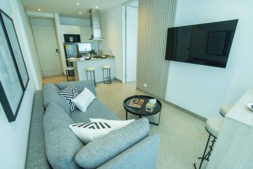 a living room with a couch with pillows and a television at Suite de lujo Distrito 90 in Barranquilla