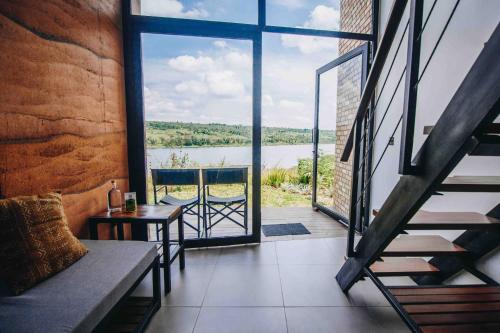 a room with a balcony with a view of a lake at UMVA Muhazi - Adults Only in Muhazi