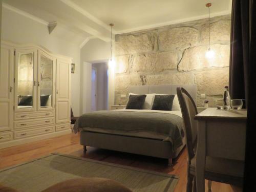 a bedroom with a bed and a stone wall at Solar dos Alperces - Serra da Estrela - Turismo de Aldeia in Travancinha