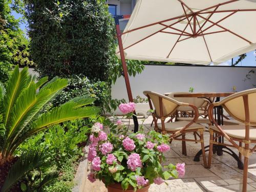 a patio with a table and chairs and pink flowers at Hotel Villa Margarit in Sarandë