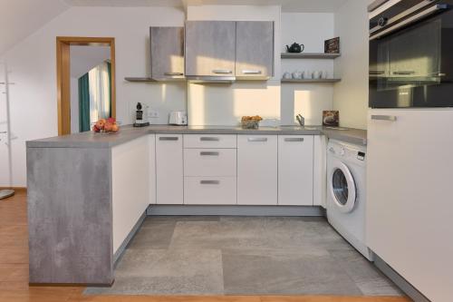 a kitchen with white cabinets and a washer and dryer at Thermen Appartements Gabriela, Appartemen 53 qm in Bad Krozingen