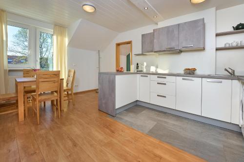 a kitchen with white cabinets and a table and chairs at Thermen Appartements Gabriela, Appartemen 53 qm in Bad Krozingen