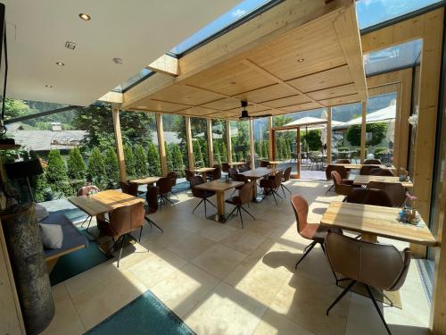 un restaurante con mesas, sillas y ventanas en Residence Hotel Alpinum en Campo Tures