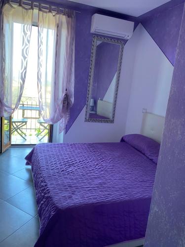 a purple bedroom with a bed and a mirror at La Bomboniera di Marco in Fabro